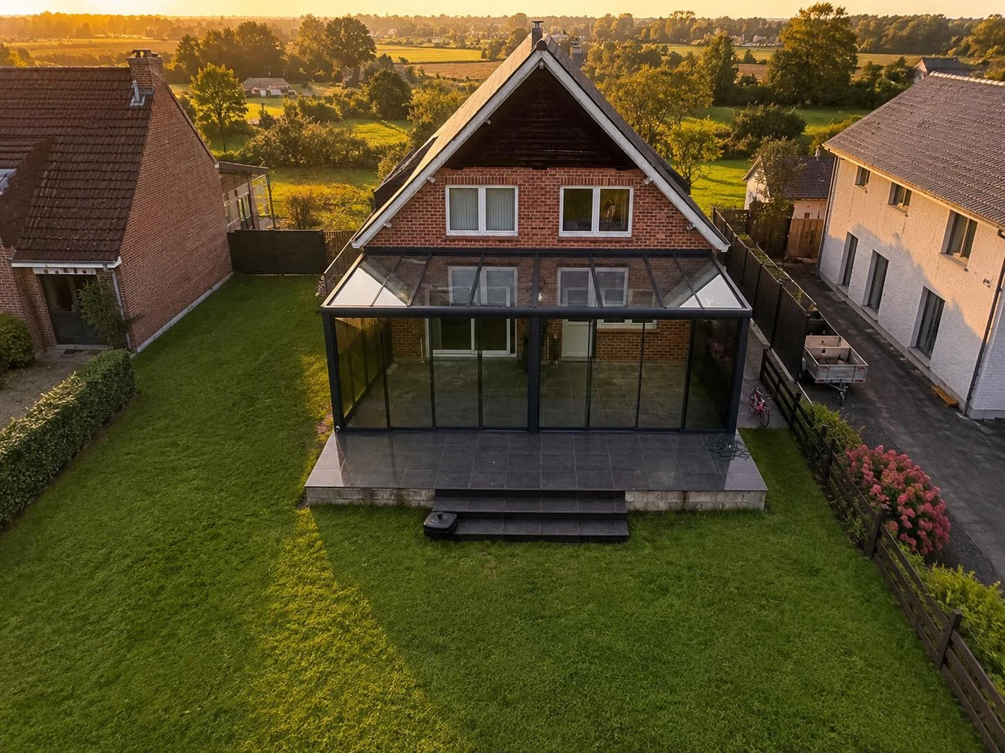 House with a glass extension across the full rear elevation, seen from above at sunset, installed by SAVA Glass