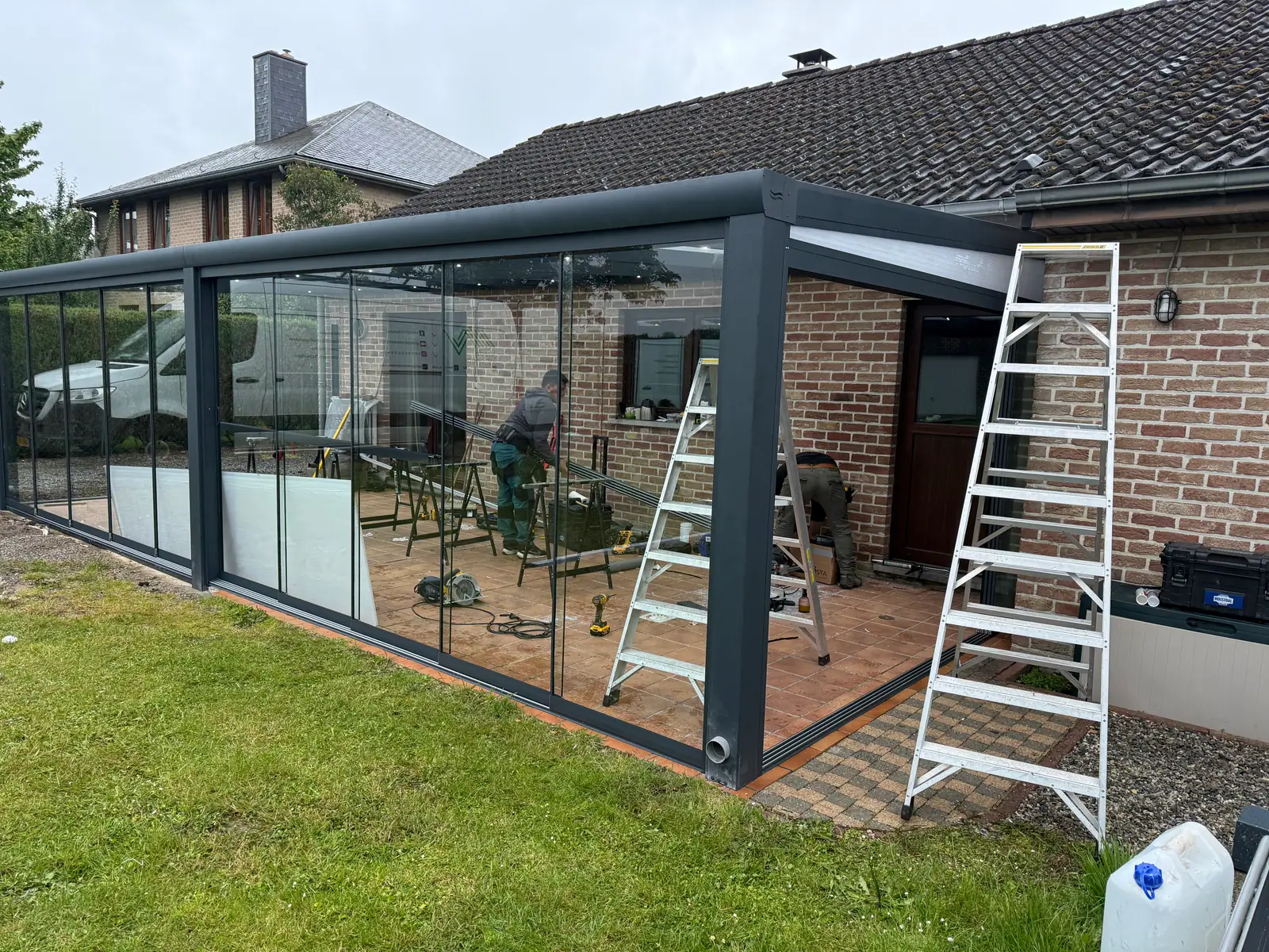Two SAVA Glass fitters building a veranda at a customer's home, with ladders and tools