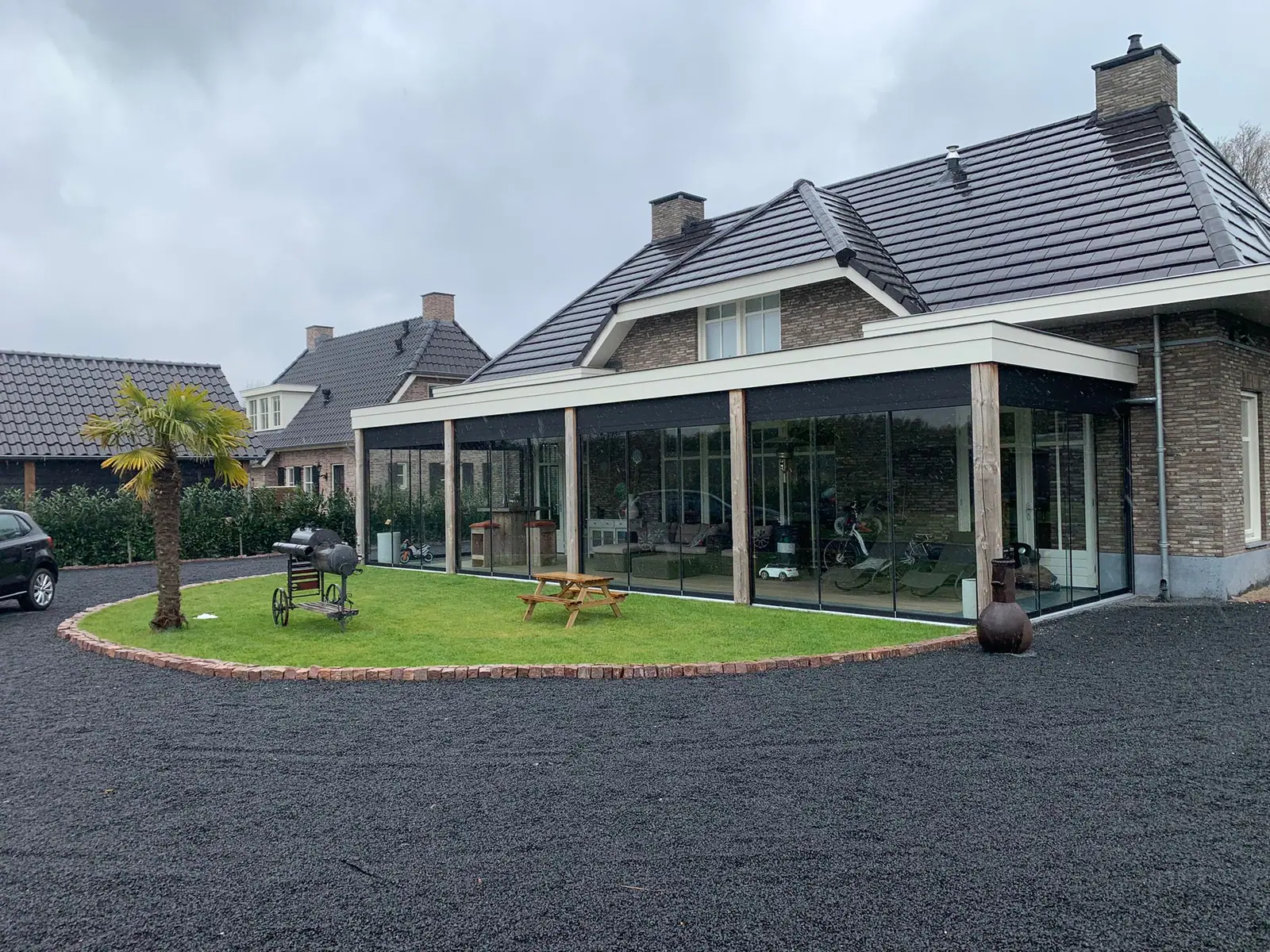 Wide veranda along the facade with wooden posts and glass sliding walls, continuing around the corner