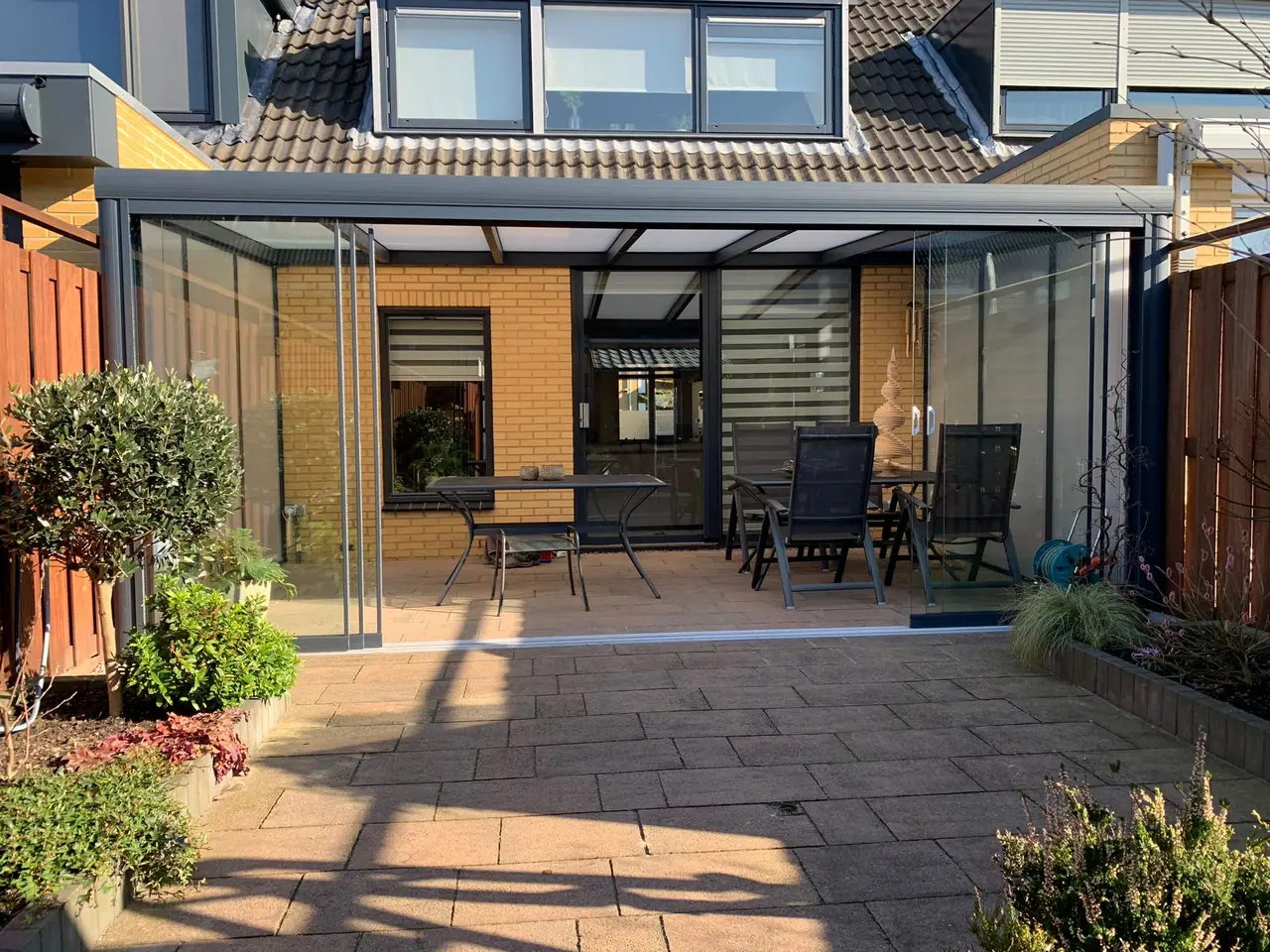 Aluminium veranda with glass sliding walls on a sunny patio